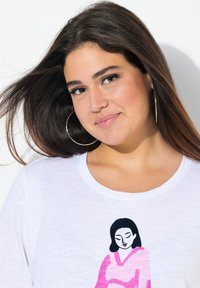 Witte t-shirt met een ronde halslijn, versierd met een roze en zwarte grafische illustratie van een vrouw. Zachte stof met een ontspannen pasvorm.