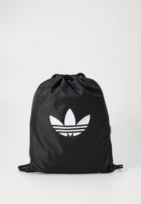 Mochila de cordão preta feita de nylon, apresentando um grande logótipo trefoil branco da Adidas e cordões ajustáveis pretos para fecho e transporte.
