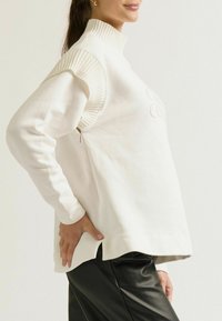 Witte sweatshirt met een geribbelde turtleneck en een ritsdetail aan de zijkant. Gemaakt van zachte stof; heeft een losse pasvorm en een subtiel reliëfdesign.