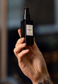 Bottiglia di vetro nera per olio da barba con dispenser a pompa, etichettata "OLIO DA BARBA", con un design semplice e dettagli in argento. Capacità di 50 ml.