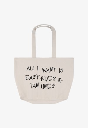 Beżowa torba na ramię z długimi rączkami i czarnym napisem z przodu: „Wszystko, czego chcę, to łatwe przejażdżki i linie opalenizny".