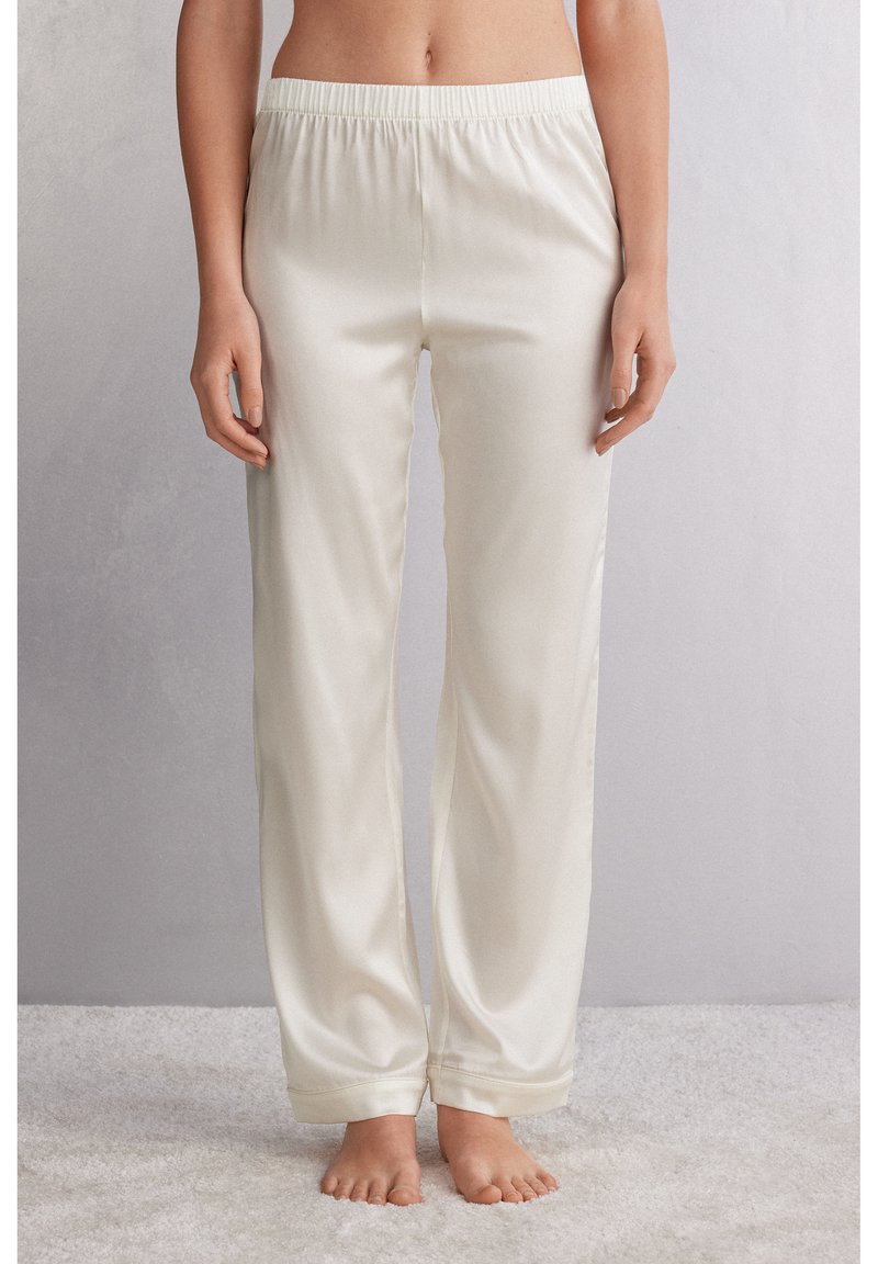 Crème-kleurige satijnen broek met een elastische tailleband, uitgevoerd in een recht slim model en met een gladde, glanzende textuur.