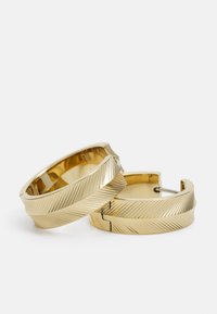 Orecchini a cerchio in oro con una texture rigata e una finitura lucida. Forma circolare con chiusura a cerniera, che offre un design moderno.