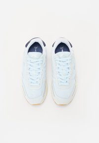 Lyseblå atletik sneakers med en myk mesh-overdel, polstret krage og hvite snørebånd. Har et minimalistisk design med en gummisåle.