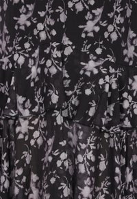 Schwarzes Kleid mit floralem Muster in Hellgrau. Es hat geschichtete Rüschen und eine transparente, fließende Stoffstruktur.