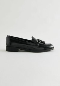 Schwarze Lackleder-Loafers mit flacher Sohle, die mit einer Quastenapplikation und einem glänzenden Finish ausgestattet sind. Der Schuh hat eine abgerundete Schuhspitze und ein Slipper-Design.