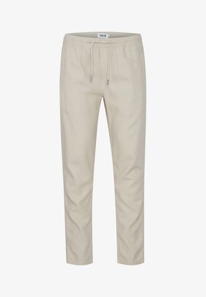 Beige drawstring pants with a relaxed fit, made from a smooth fabric. Features side pockets and elastic waistband with metal tips on the drawstrings.
