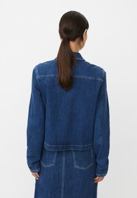 Veste en jean à manches longues, avec un léger effet délavé et une coupe courte. Dotée de coutures contrastantes et de deux poches arrière. Couleur : bleu foncé.