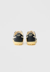 Mustad nahast tossud beežide aktsentide ja kollaste kummist tallaga. Tagaküljel on logo ning pealmine osa on tekstureeritud disainiga.