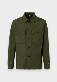 Olive roheline pika käisega nööbitav särk, millel on kaks nööpidega rinda taskut ja kaelus, esitatud tasasel valgel taustal.