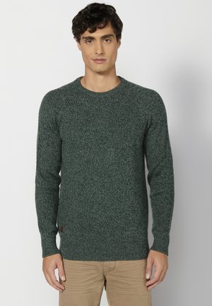 Groene gebreide trui met een gestructureerd oppervlak, ronde halslijn en lange mouwen. Bevat geribde manchetten en een klein logo aan de onderkant.