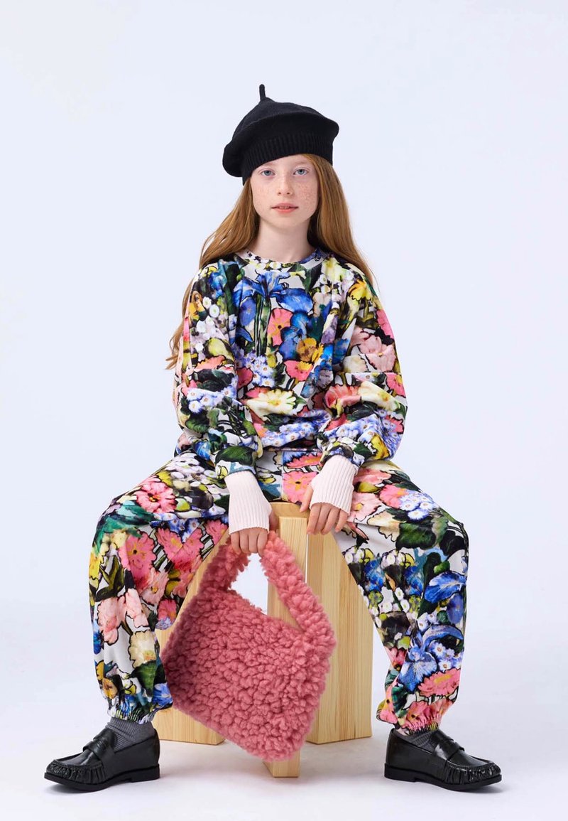 Multicolored floral print outfit in soft fabric, black beret, holding a fluffy pink handbag, and wearing black shoes with a textured finish.