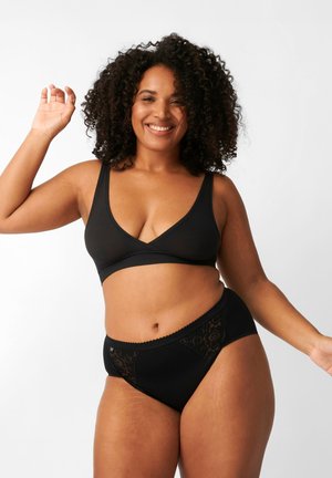 Bralette nera con scollo a V e spalline larghe, abbinata a perizoma nero con inserto in pizzo e bordi ondulati.