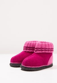 Vilt slippers in levendige tinten van roze, met een gebreide rand en textuuroverlagen, en een contrasterende grijze rubberen onderkant.