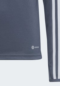 Maglietta sportiva grigia con tre strisce bianche lungo le maniche, tessuto testurizzato e logo "AEROREADY" sull'orlo del lato anteriore.