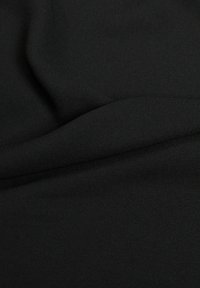 Tissu noir lisse avec des plis doux mettant en valeur la texture et le tomber du matériau.