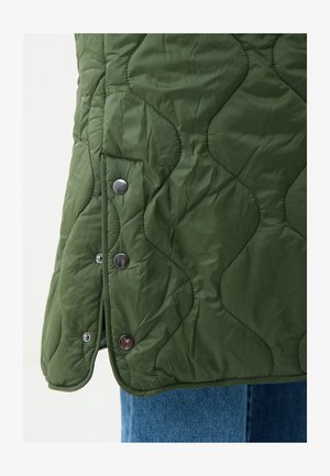 Grüner gesteppter Westen mit wellenförmigem Muster, ausgestattet mit silbernen Druckknöpfen an der Seite und einer glatten, leichten Textur.