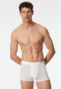 Boxer-briefs blancs en coton avec une taille élastique douce et une texture lisse. La coupe ajustée améliore le confort et le soutien.