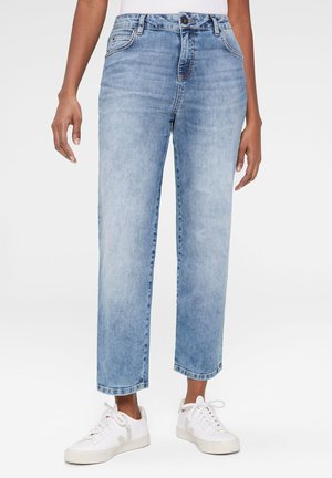 Hellblaue High-Waist-Jeans mit geradem Schnitt, vier Taschen, subtilen Ausbleichungen und genähten Details, kombiniert mit weißen Sneakern.