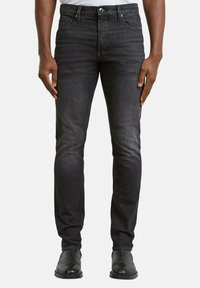 Vaqueros de mezclilla negra con corte slim, que cuentan con un diseño clásico de cinco bolsillos y un desvanecimiento sutil. Detalles cosidos cerca de la cintura.