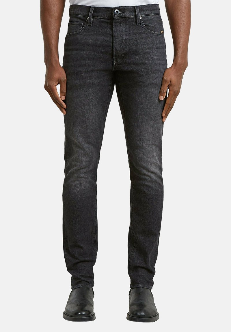 Vaqueros de mezclilla negra con corte slim, que cuentan con un diseño clásico de cinco bolsillos y un desvanecimiento sutil. Detalles cosidos cerca de la cintura.