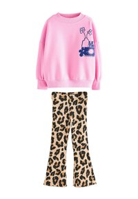 Lyserød sweatshirt med grafiske tryk og puffede ærmer, kombineret med vidde leopardmønstrede bukser med beige bund og sorte pletter.