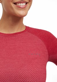 Rood sportshirt met een gestructureerd, diamantpatroon op het lichaam en ribbelaccenten op de mouwen. Bevat een logo op het borstgebied.