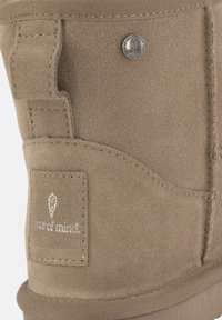 Stivale in suede marrone con finitura testurizzata, dotato di un bottone argentato, dettagli cuciti e un patch con il logo "peace of mind".