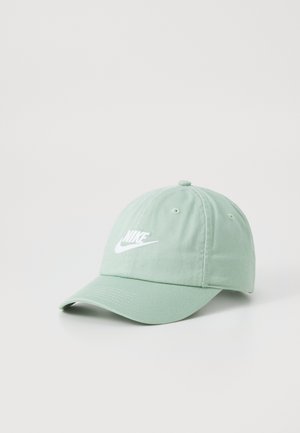 Gorra de algodón color verde claro con correa ajustable, visera curvada y logo blanco bordado en la parte frontal. Diseño de seis paneles con orificios de ventilación.