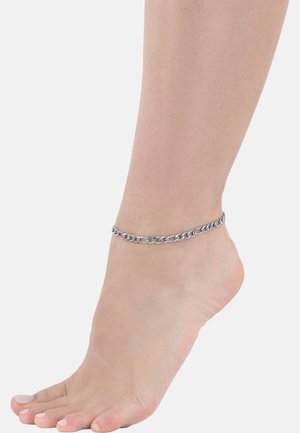 Cavigliera in argento appoggiata su una caviglia nuda, caratterizzata da anelli ovali interconnessi con una finitura lucida. La pelle mostra una leggera texture.
