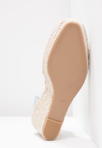 Semelle d’une espadrille compensée tressée beige pour femme, taille 4/37 indiquée sur la semelle en caoutchouc.