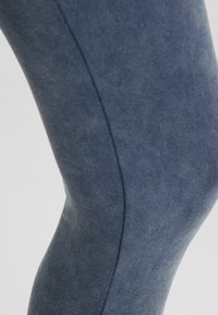 Marina blå leggings gjorda av mjukt, elastiskt tyg, med en slät textur och kurviga sömmar för en åtsittande look.