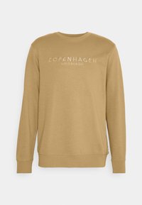 Sweatshirt couleur moutarde avec un col rond, des manches longues et le texte brodé "COPENHAGEN LINDBERGH" sur le devant.
