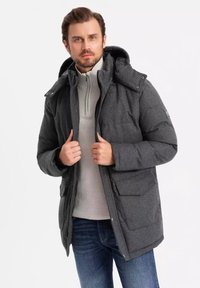 Parka grigia isolata con cappuccio, dotata di tasche frontali, chiusura con zip e un maglione lavorato a maglia sotto.