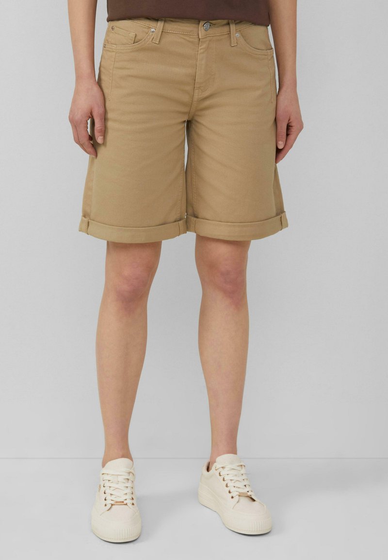 Shorts beiges jusqu'aux genoux avec ourlets retroussés, en denim de coton, dotés de poches avant et d'une fermeture à bouton en métal à la taille.