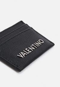Črni usnjeni etui za kartice z teksturirano površino in srebrnim logotipom Valentino ter tremi režami za kartice, prikazan na beli podlagi.