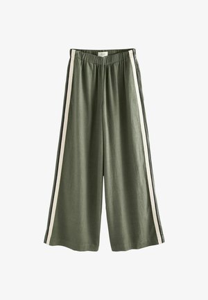 Pantalon large vert olive avec taille élastique et bandes latérales blanches et noires, fabriqué dans un tissu léger.