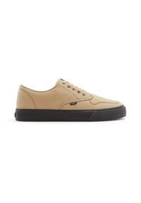 Sneakers in tela beige con punta tonda, suola in gomma nera, cinque occhielli e dettagli cuciti sulla parte superiore. Etichetta con logo di lato.