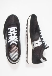 Czarne sportowe sneakersy wykonane z siateczki i zamszu. Posiadają białe sznurówki, srebrne akcenty po bokach oraz strukturę podeszw dla lepszej przyczepności.