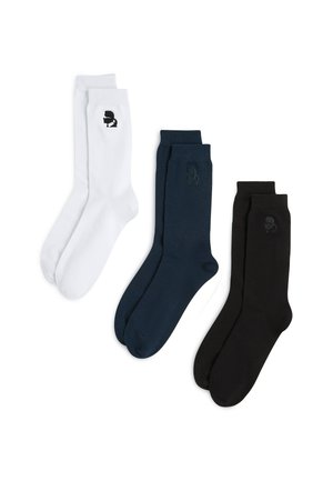 Tres pares de calcetines de tripulación: blancos con logo negro, azul marino oscuro y negro sólido, todos en material suave con ribetes en la parte superior para un ajuste cómodo.