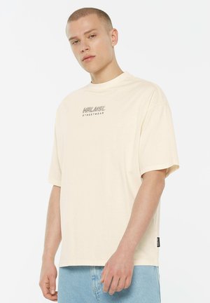 Übergroßes T-Shirt in Cremefarbe aus Baumwolle, mit rundem Ausschnitt und kurzen Ärmeln, versehen mit einem aufgedruckten Logo auf der Brust.