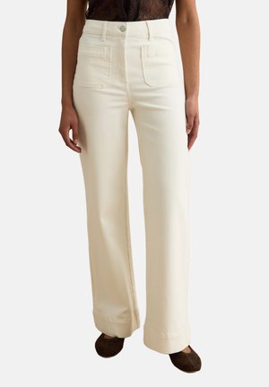 Pantalones anchos de talle alto en color crema, con bolsillos parche delanteros y cierre de botones, combinados con zapatos planos marrón oscuro.