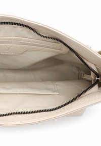 Wnętrze beżowej torebki o teksturowanej powierzchni z ciemnym zamkiem błyskawicznym. Posiada kieszeń zamykaną na zamek oraz dodatkową kieszeń na suwak dla lepszej organizacji. Gładka podszewka z tkaniny.