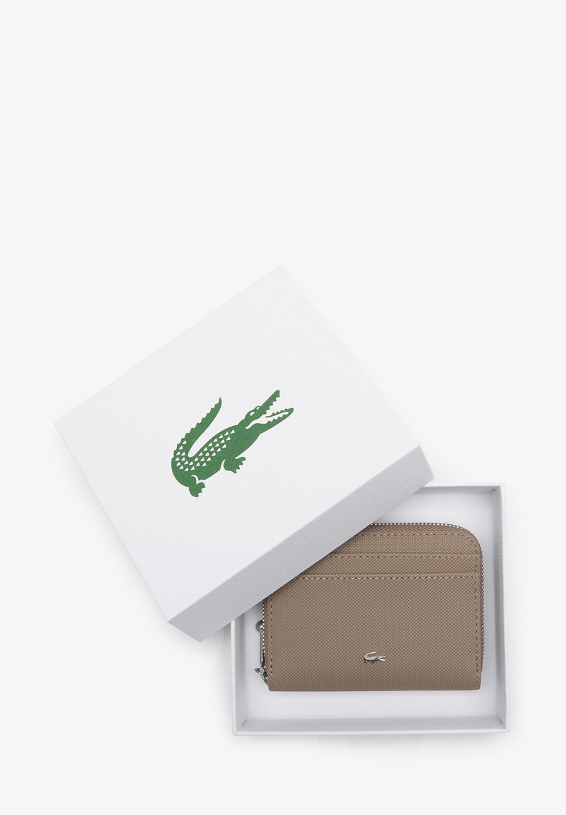 Beige Geldbörse mit Reißverschluss, mehreren Kartenfächern, strukturiertem Finish, silbernem Logo, präsentiert in einer weißen Schachtel mit grünem Krokodilsymbol.