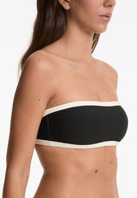 Črn bandeau bikini zgornji del s kremnim robom, ki se ponaša z gladko teksturo in minimalističnim oblikovanjem, zasnovan za nošenje brez naramnic.