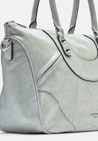Jasnozielona skórzana torebka o fakturowanym wykończeniu, z metalowymi elementami w kolorze srebra, dwoma uchwytami i zakrzywionymi akcentami. Subtelny detal z logo widoczny.