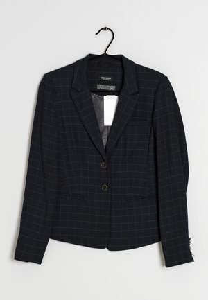 Sort blazer med hvidt ternet vinduesmønster, to knapper, hakkede revers og forlommer hængende på en sort bøjle mod en hvid baggrund.
