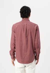 Langarmhemd in staubigem Rose, aus leichtem Stoff. Mit einem Knopfkragen und einer Rückenfalte für Bewegungsfreiheit.