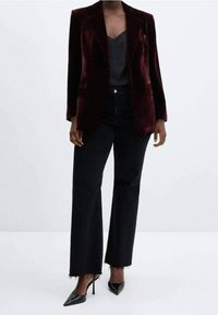 Blazer en velours bordeaux à coupe ajustée, avec des revers crantés, associé à un haut gris et un pantalon en denim noir taille haute. Escarpins noirs pointus.