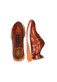 Bruine leren sneakers met een geperforeerd ontwerp, bruine veters en een oranje rubberen zool. Rond neus en contrasterende kleuraccenten.